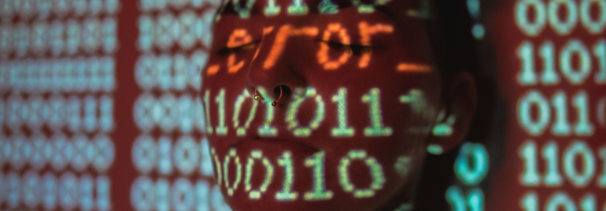 Man with word "error" and zeroes and ones projected over his face.Photo by Jayson Hinrichsen on Unsplash
